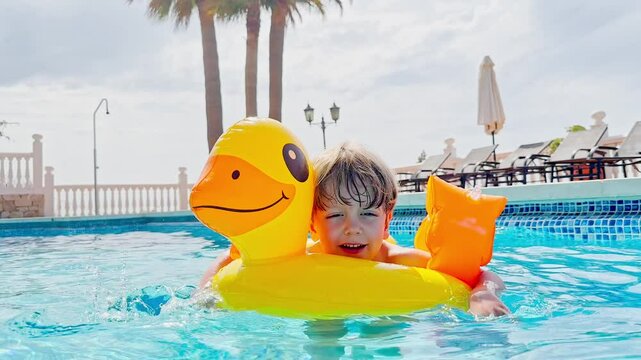Happy child plays at a pool with duck floaty laughing, smiling