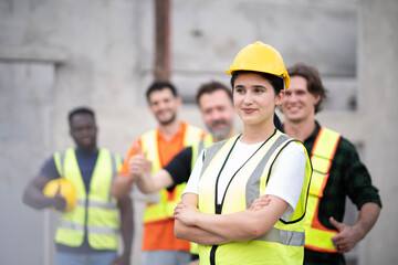 Young White engineer woman cross arm at chest looking front visually with smile at work site. Portrait of engineer wearing white hard hat with blur smile of teamwork.