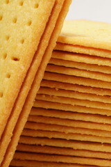 Rectangular, savory salty cheese-flavored biscuits with a golden-yellow color, neatly stacked. Perfect as a snack. Photographed on a white background.