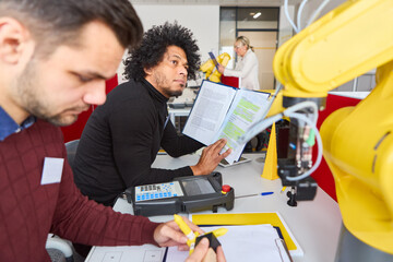 Engineers programming industrial robots with gripper arms in technology training center