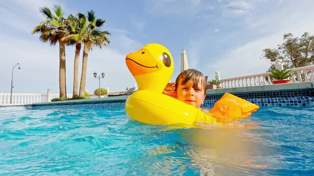 Kid jumps into refreshing pool, and swim toward camera in summer
