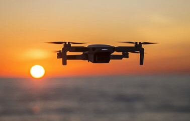 Drone flying in the sky against the backdrop of a bright sunset. Radio-controlled quadcopter with a...