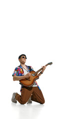 Poster. Stylish young man, bass guitarist kneels dramatically while playing electric guitar against...