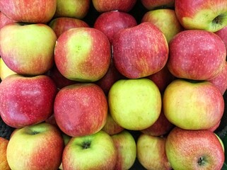 Closeup detail of the surface texture background of a pile of stock red apples at a fruit stand. Stacks of fresh red apples for sale at the market.