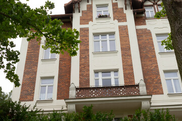 A considerable and expansive brick building featuring a balcony and a lovely tree positioned right in front of it