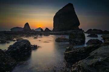 Serene coastal sunset with rocky formations.