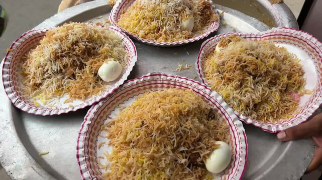 Four plates of Kolkata style mutton biryani served with potato and egg at a roadside stall in Kolkata.