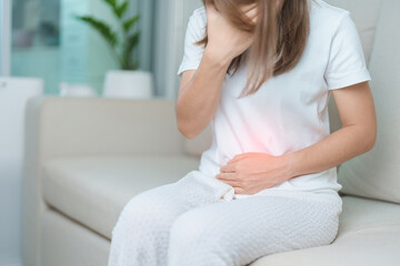 woman having abdomen ache due to Stomach pain, digestion with constipation or Diarrhea from food poisoning, female problem and Endometriosis, Hysterectomy, Stomachache and Menstrual on sofa at home