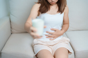 Lactose intolerance and Milk allergy concept. woman hold Milk glass and having abdominal cramps and...