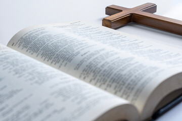 Fototapeta premium Wooden religion cross and opened blue book of Holy Bible isolated over white background. Symbol of faith in God, Christianity Feast