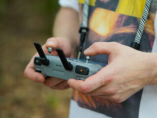 Die Hand h&auml;lt den Joystick, um die Drohne zu steuern