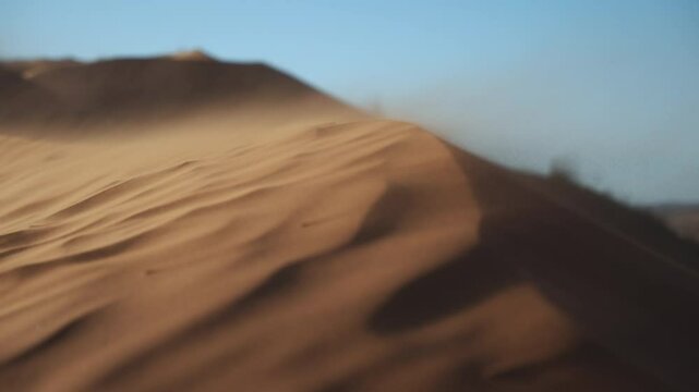 Very close up super slow motion shot of a dune edge with the wind carrying the sand on a sunset in the dunes of Namibia, Africa