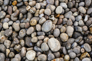 A collection of smooth, rounded pebbles in various shades of grey and beige, closely packed together