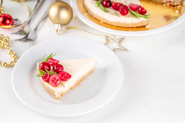 Tasty Christmas cheesecake with cranberries and rosemary decorated like Christmas wreath. Simple elegant winter white dessert 