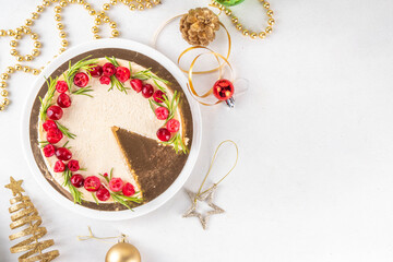 Tasty Christmas cheesecake with cranberries and rosemary decorated like Christmas wreath. Simple elegant winter white dessert 