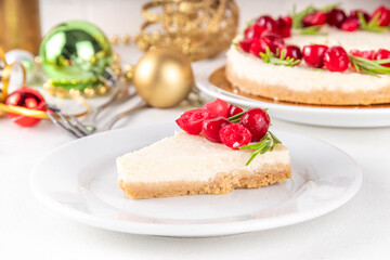 Tasty Christmas cheesecake with cranberries and rosemary decorated like Christmas wreath. Simple elegant winter white dessert 