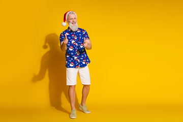 Full body portrait of stylish santa point fingers you empty space new year xmas print shirt isolated on yellow color background