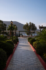 A serene pathway leads to a tranquil waterfront at a beachside resort with lush greenery and inviting lounge chairs