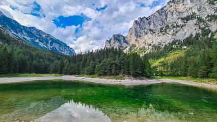 Serene alpine lake Gruener See reflects majestic mountain peak Messnerin, Hochschwab region, Styria, Austria. Wanderlust Austrian Alps. Clear water mirrors the towering ridges and lush idyllic forest