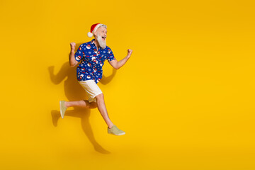 Full size photo of stylish modern santa raise fists jump empty space wear x-mas winter print shirt isolated on yellow color background