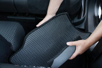 Man taking grey rubber car mat from auto, closeup