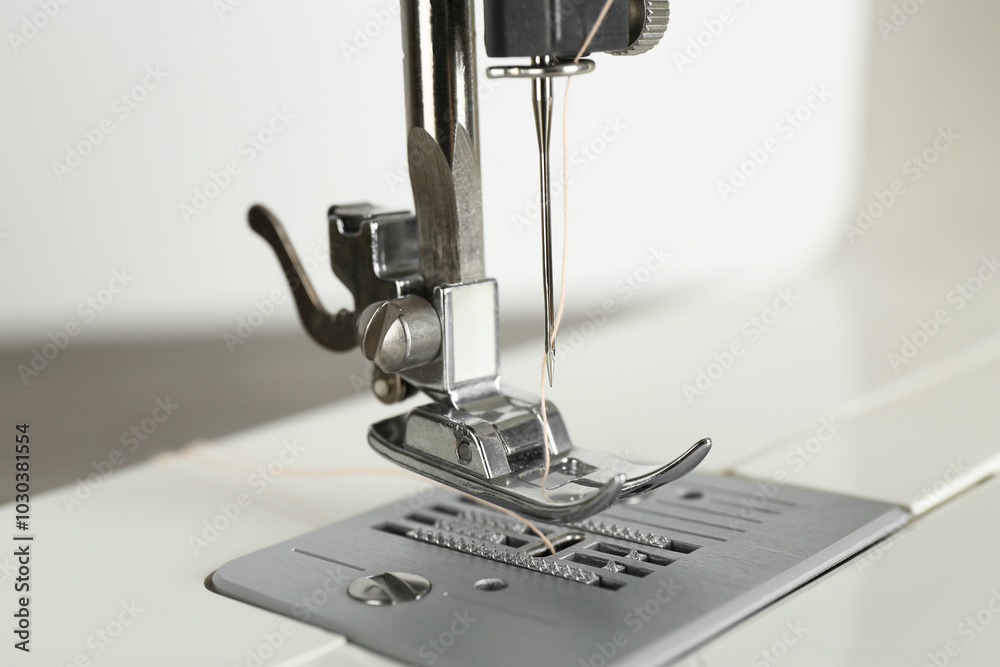 Canvas Prints Sewing machine with beige thread on light background, closeup