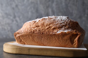 Tasty sponge cake with powdered sugar on grey table, closeup