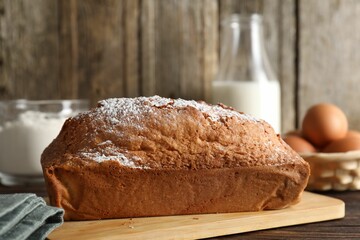 Tasty sponge cake with powdered sugar on wooden table, closeup