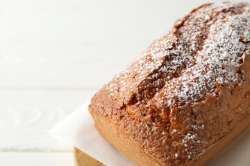Tasty sponge cake with powdered sugar on white table, closeup. Space for text