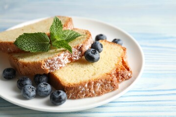 Freshly baked sponge cake, blueberries and mint on light blue wooden table, closeup