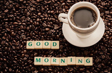 Beans, cup and letters with coffee, words and liquid for brewing, roasting and organic caffeine industry. Tiles, texture and spell for espresso, grinding and beverage production with good morning