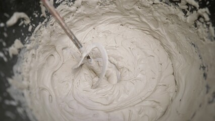 Construction worker mixing cement plaster with electric mixer.