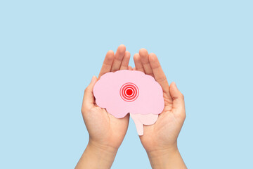 Hands holding brain as pain red circle on light blue background. Concept of headache, stroke...