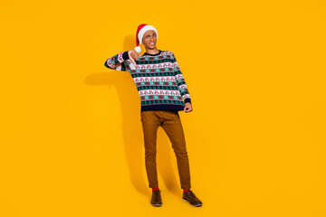 Full size photo of nice young male show ugly sweater thumb down wear ornament christmas outfit theme party on yellow color background