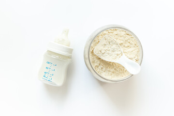 Jar of powdered milk for baby food with bottle of milk and spoon, top view