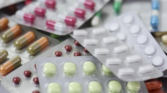 Closeup of pile of pills in blisters rotating counterclockwise in a loop