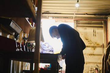A young man in a garage working with electrical equipment, tinkering with something
