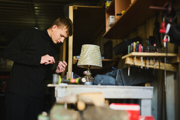 A young man in a garage working with electrical equipment, tinkering with something
