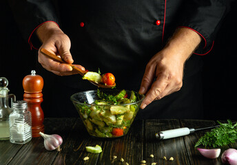 Cooking vegetable mix on kitchen table in bowl. Chef holds wooden spoon with fresh vegetables.