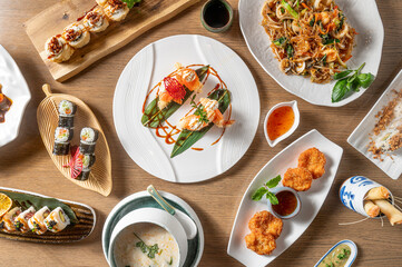 Asian , Chinese, Japanese and Thai food composition horizontally on wooden background, from above, with shrimp, hosomaki uramaki, soy noodles and sushi