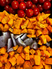 Bright vegetables cut into pieces. Roasting vegetables. Healthy food. Pumpkin, tomatoes and onions laid out in a row.