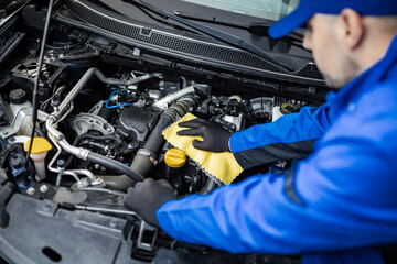 Technician inspects and cleans engine components inside a vehicle at an automotive workshop during...
