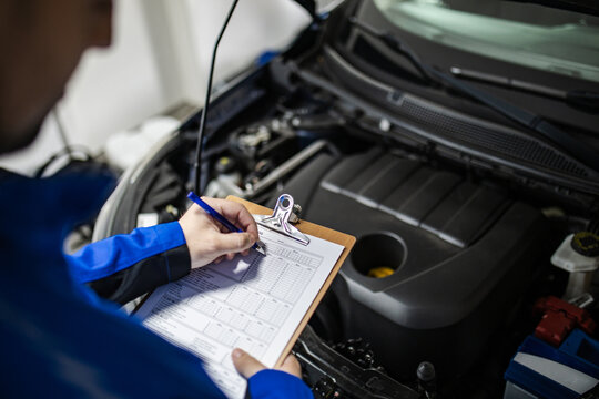 Mechanics inspect engine components and perform routine checks in an auto repair shop during the day