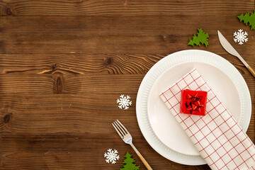 Red colored table setting flatlay for Christmas and New Year Eve. Empty plate with cutlery and decoration, top view