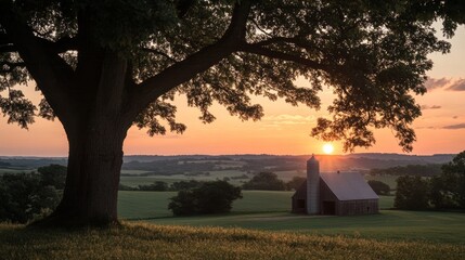 Naklejka premium Scenic Countryside Sunset with Barn and Silhouetted Tree
