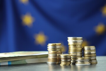 Stacks of coins and euro banknotes on grey table, closeup