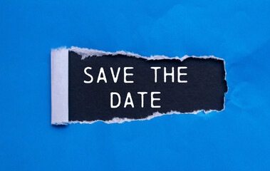 Save the date message written on ripped torn blue paper with black background. Conceptual save the...