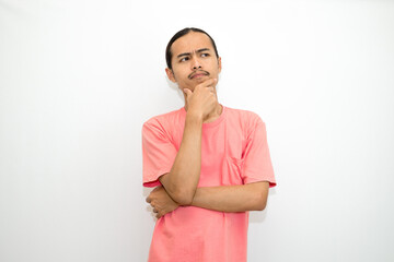 Asian, Indonesian man standing with his hand on his chin and head as if in deep thought, thinking...