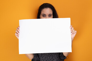 Beautiful black haired latin american woman holding blank banner with confident face, standing.