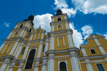 Low angle view of majestic church Basilika Mariastrost with two magnificent bell towers in Graz, Styria, Austria, Europe. Sky filled with fluffy white clouds; heaven atmosphere on religious site.